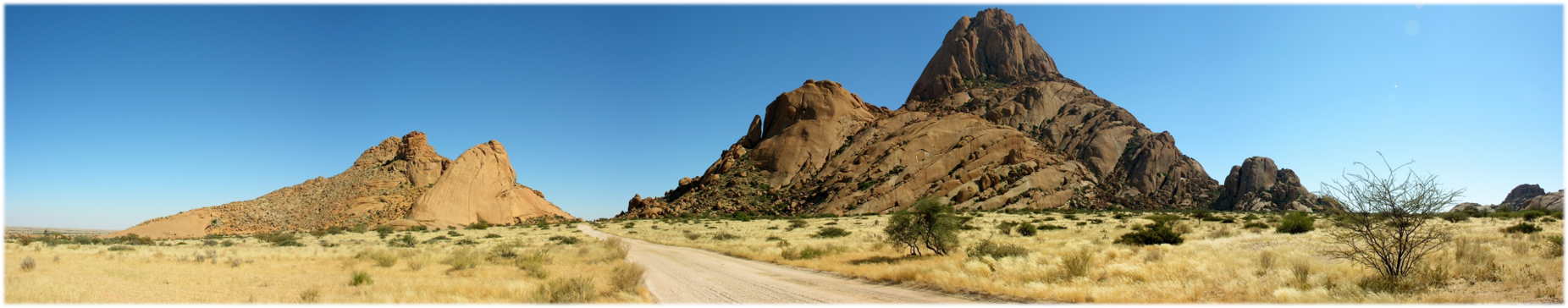 Desert vista with a dirt road between two rock formations.